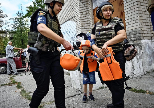 ウクライナ南部ザポリージャ州で、避難する住民に防弾チョッキを着せる警察官